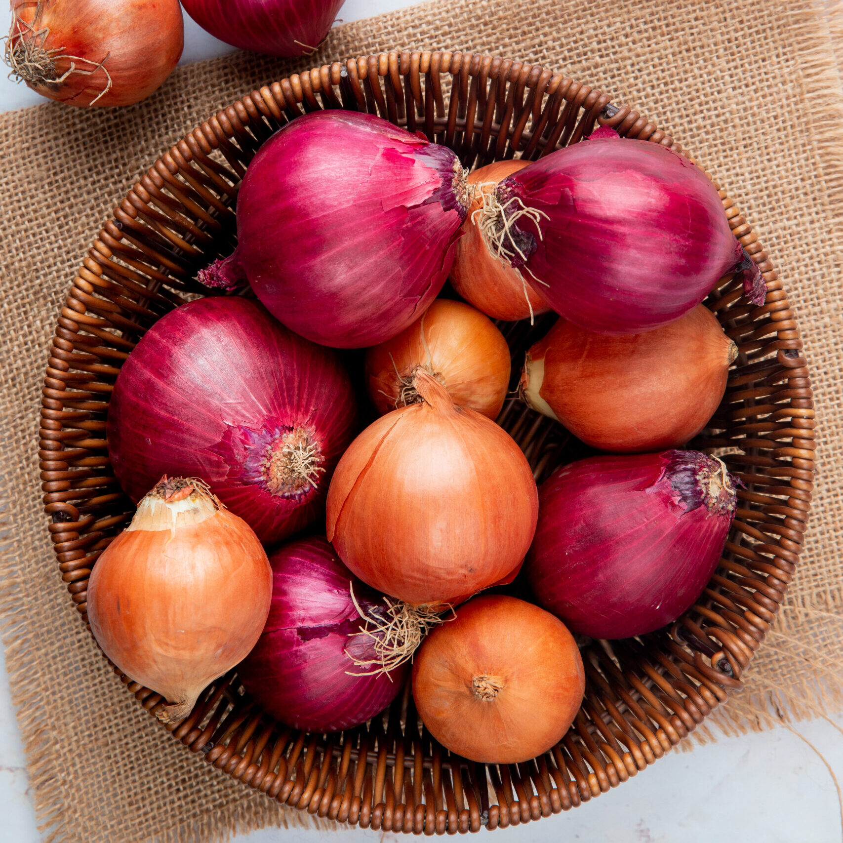 Fresh red and golden onions arranged in a basket.